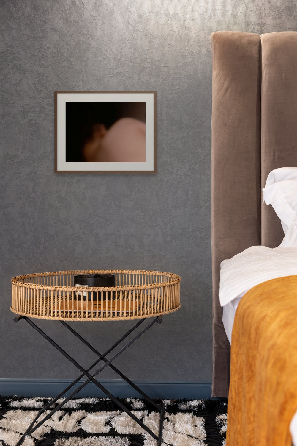 A fine art photo print of a body in the dark, hanging on the wall of a bedroom.