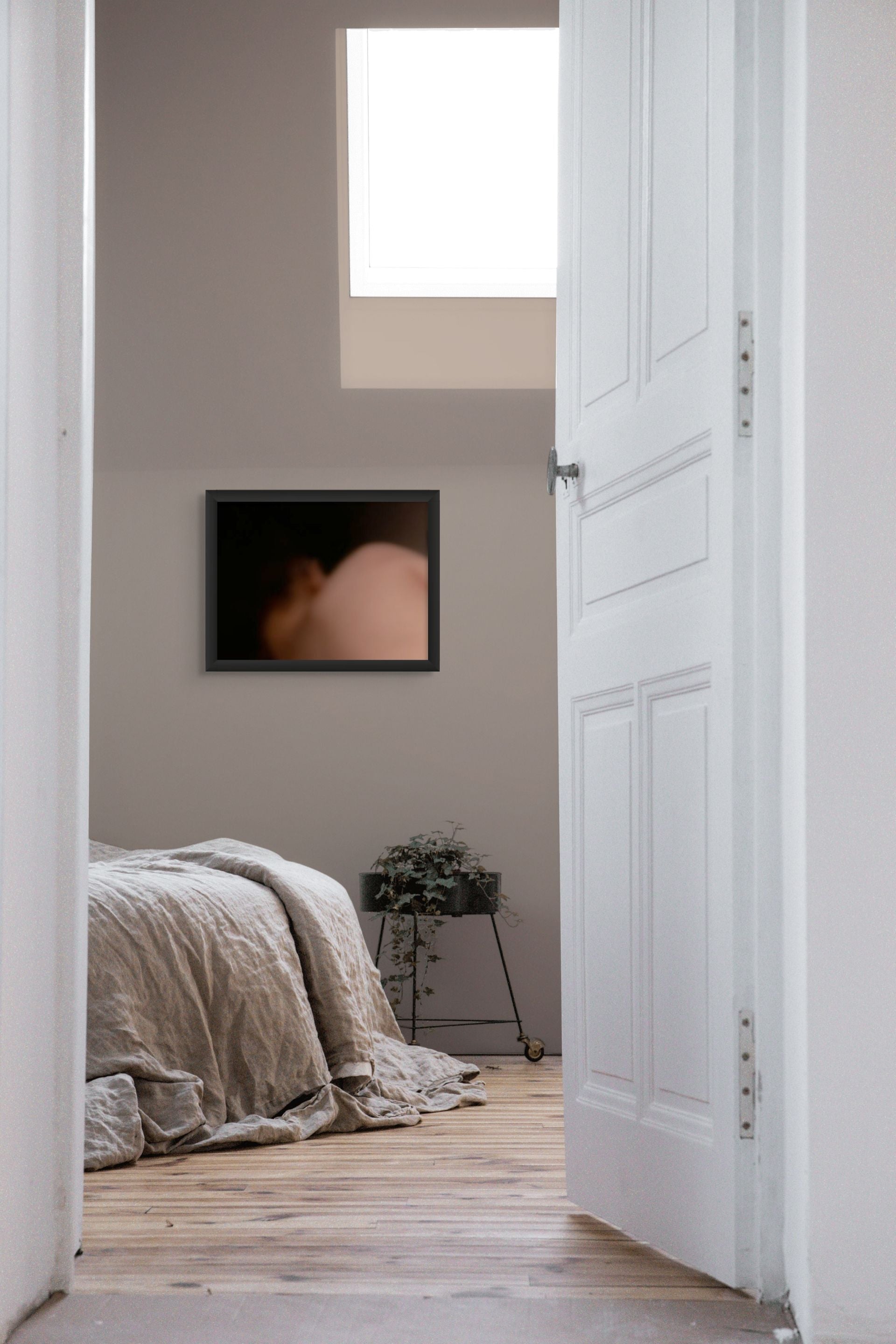 A fine art photo print of a body in the dark, hanging on the wall of a bedroom.