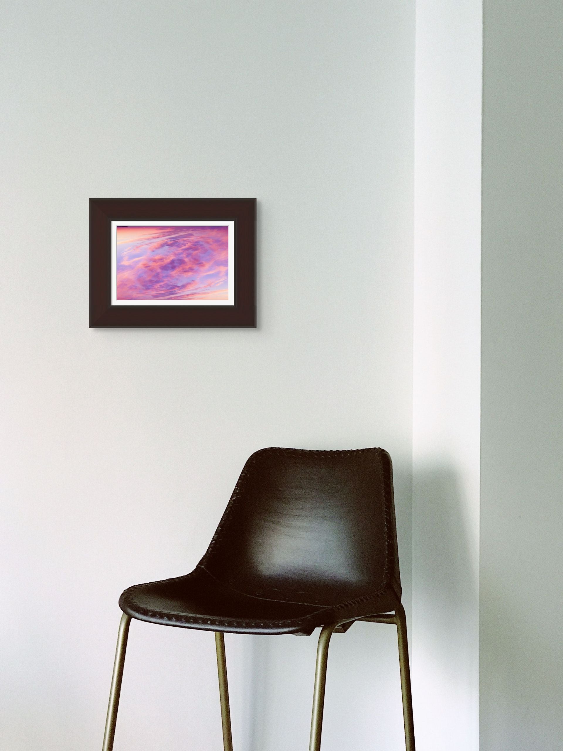 A splash of color in the form of an abstract fine art photograph depicting a double exposure of a sunset sky over cape cod. It is framed and hung on the wall of a sleek interior.