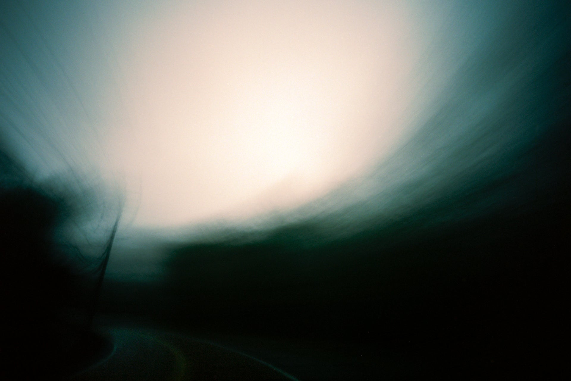 Green and black abstract photo of a road at dusk.