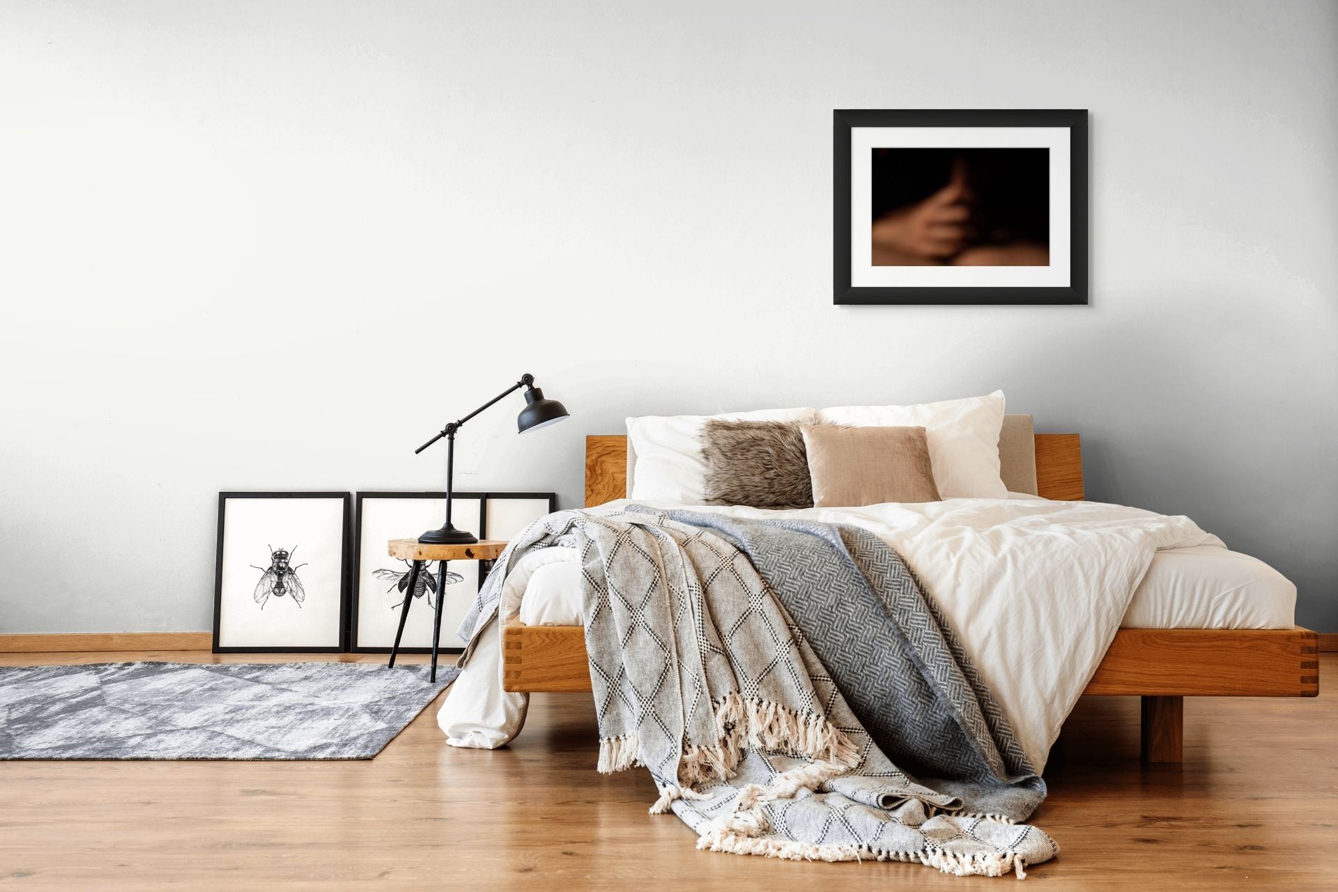 A print of an abstract photo, framed in black and hanging in a modern natural bedroom.